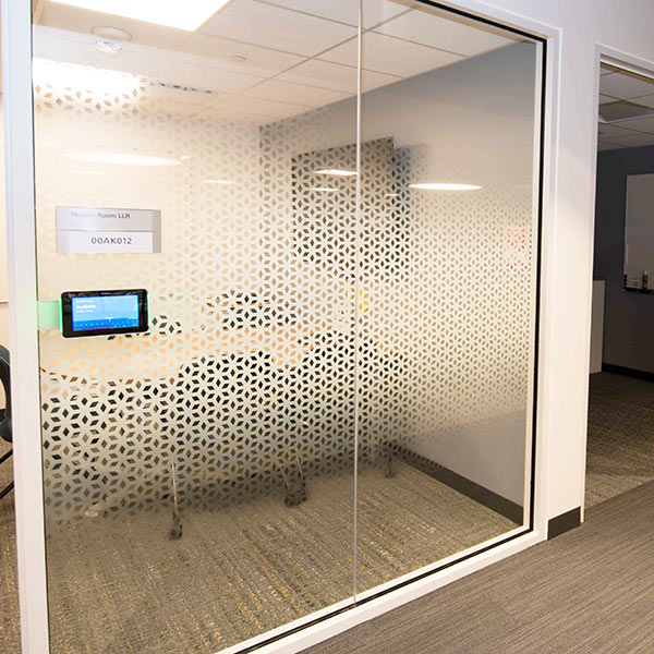 A glass office partition with a geometrical design across the middle.