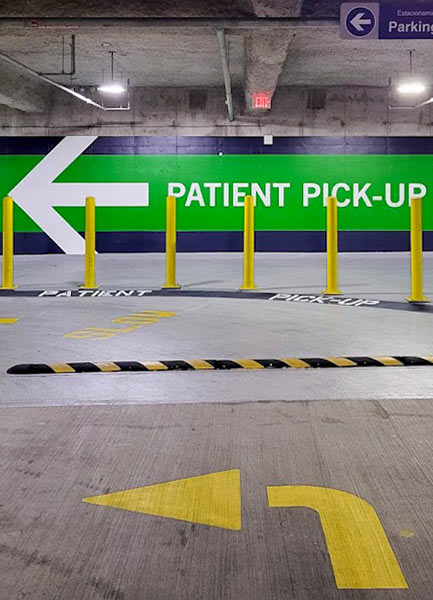 A wall in a parking structure reads "Patient Pick Up" with a large arrow pointing left.