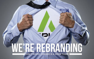 A person pulls open their blue button-up shirt to reveal the upper portion of the Amplify logo on the t-shirt beneath it. The out shirt features the upper portion of the West Allis Blue logo, and the bottom of the image reads, "We're Rebranding. Don't worry, change is a good thing!"